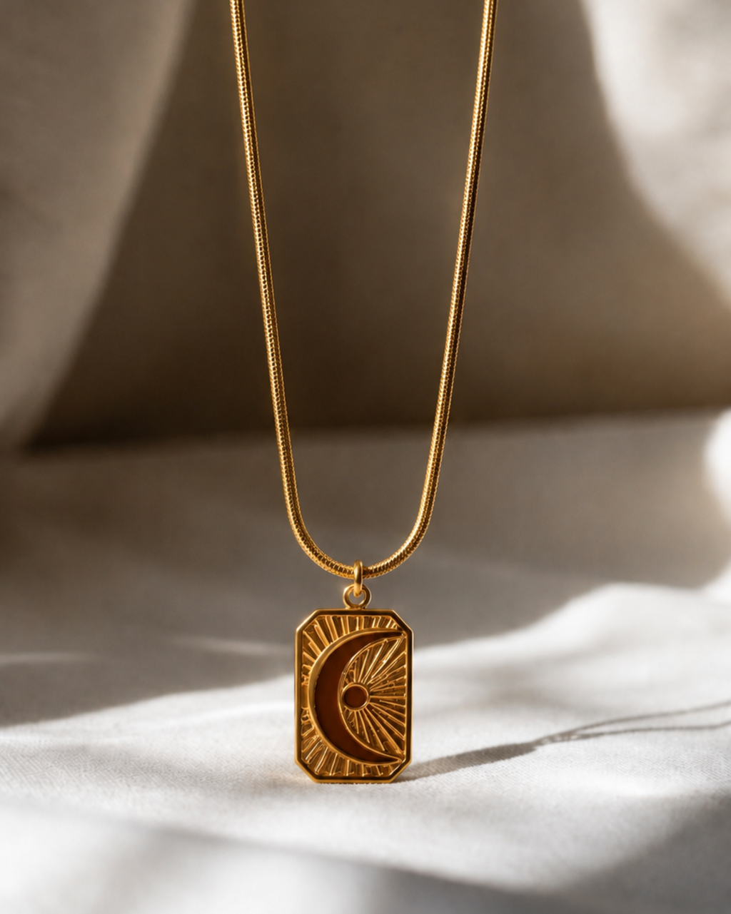 Gold necklace with a decorative pendant on a neutral background