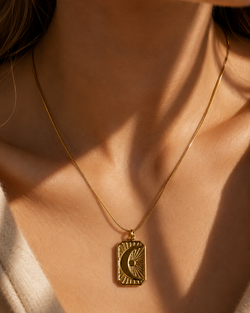 Gold necklace with a pendant on a person's neck