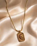 Gold necklace with a pendant on a beige fabric background