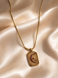 Gold necklace with a pendant on a beige fabric background