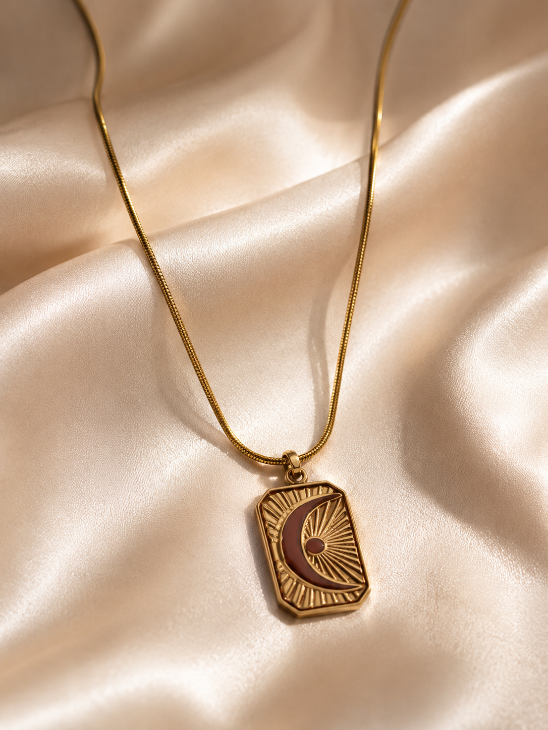 Gold necklace with a pendant on a beige fabric background