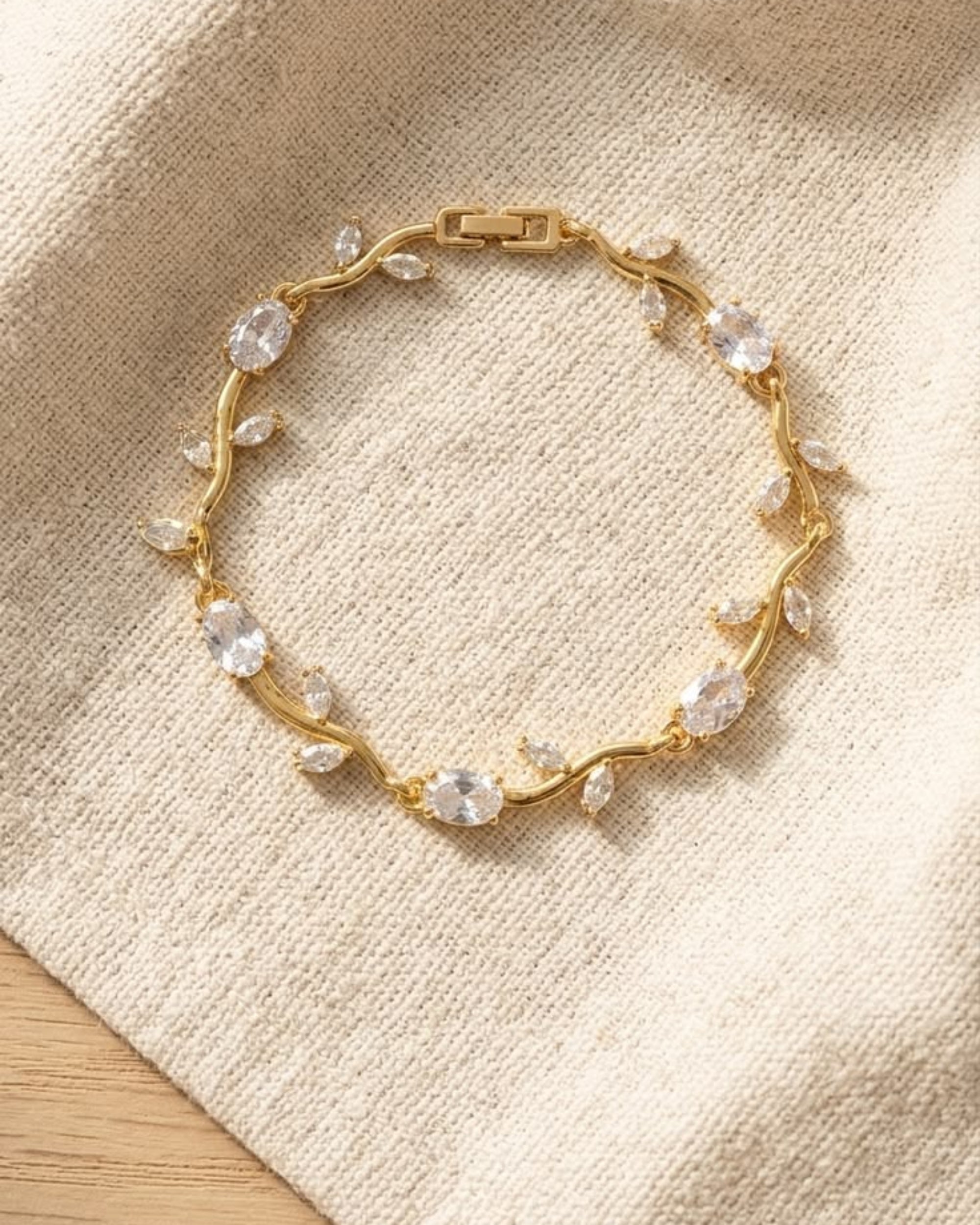 Gold bracelet with clear stones on a beige fabric background